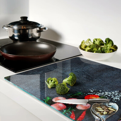 Tocător din sticlă Legume și condimente pe un fundal închis