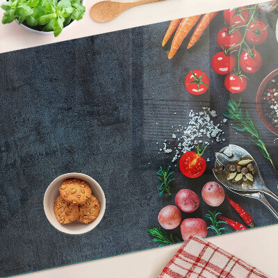 Tocător din sticlă Legume și condimente pe un fundal închis