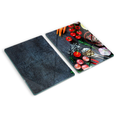 Tocător din sticlă Legume și condimente pe un fundal închis