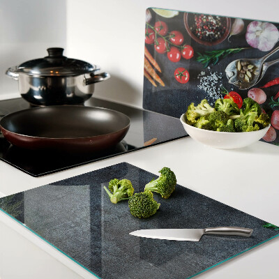 Tocător din sticlă Legume și condimente pe un fundal închis