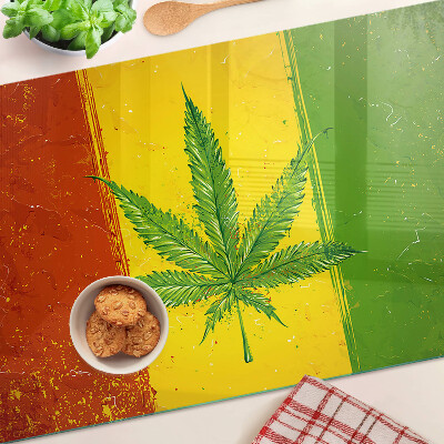 Tocător din sticlă Frunză de canabis pe un fundal colorat